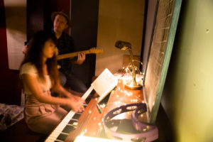 Two musicians performing: one playing piano, the other playing electric guitar.