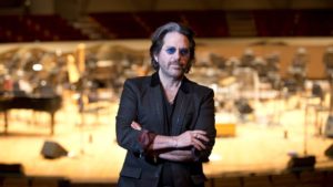 Kip Winger stands in front of a stage.