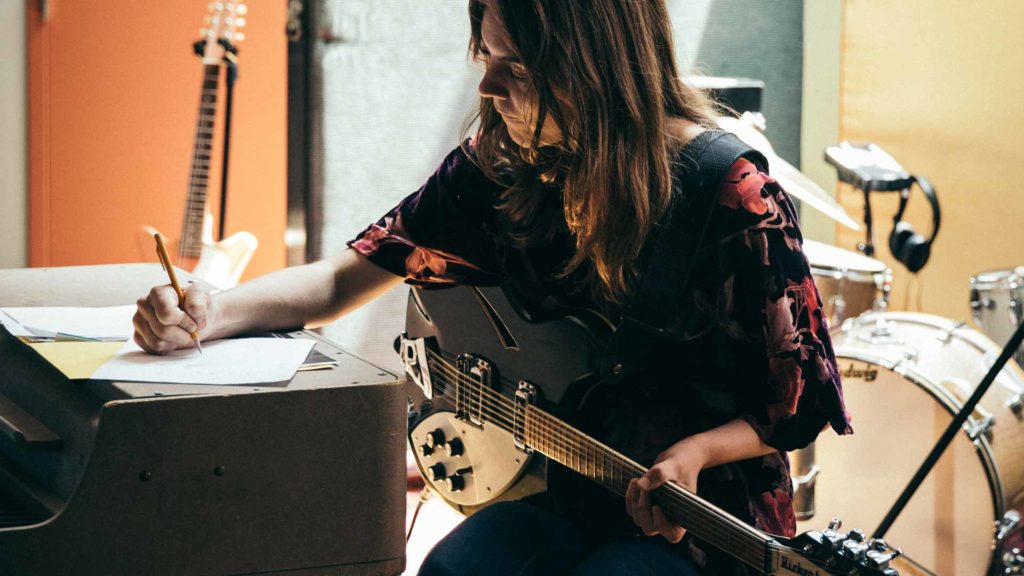 A woman writing melody on guitar