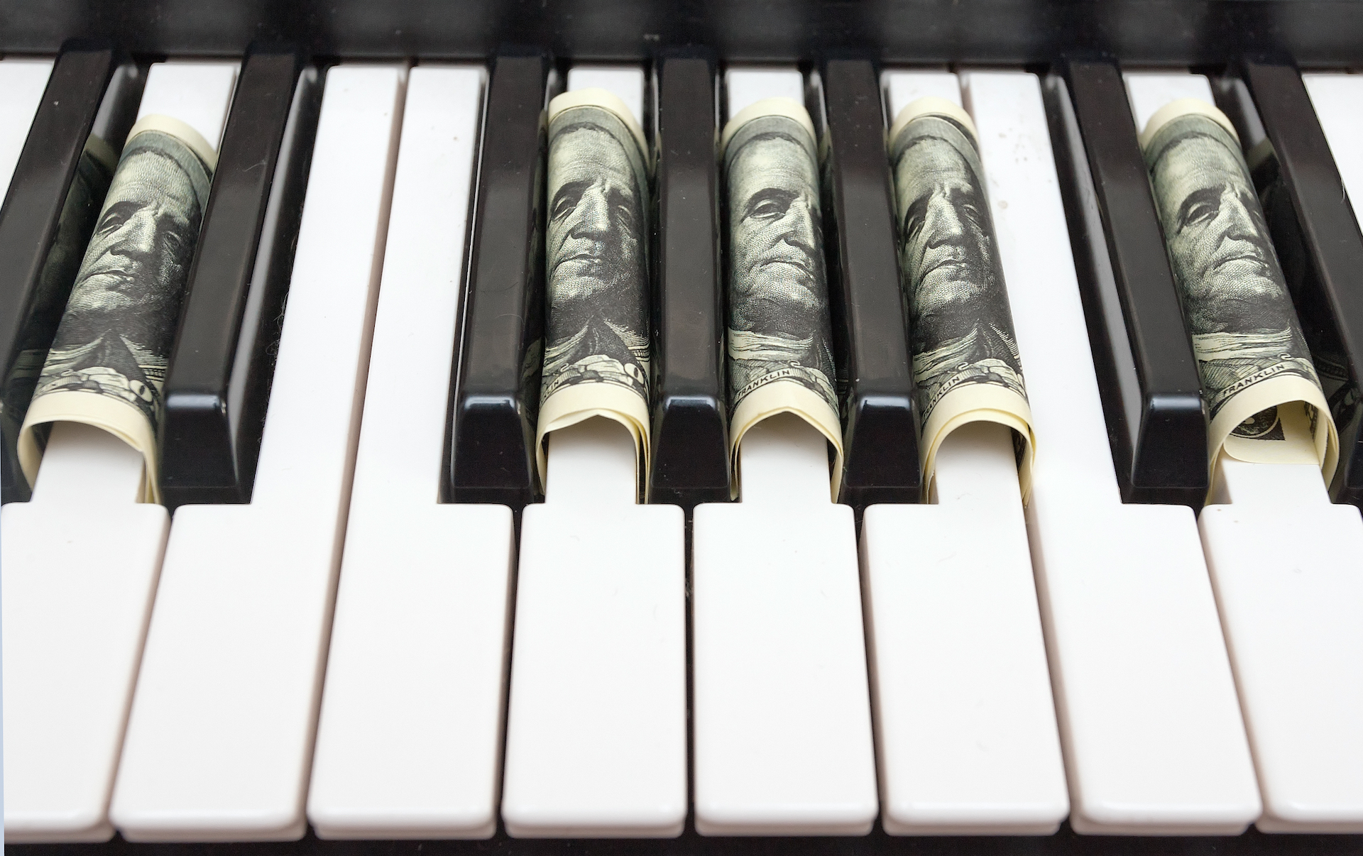 A piano with 100 dollar bills tucked into the keys.