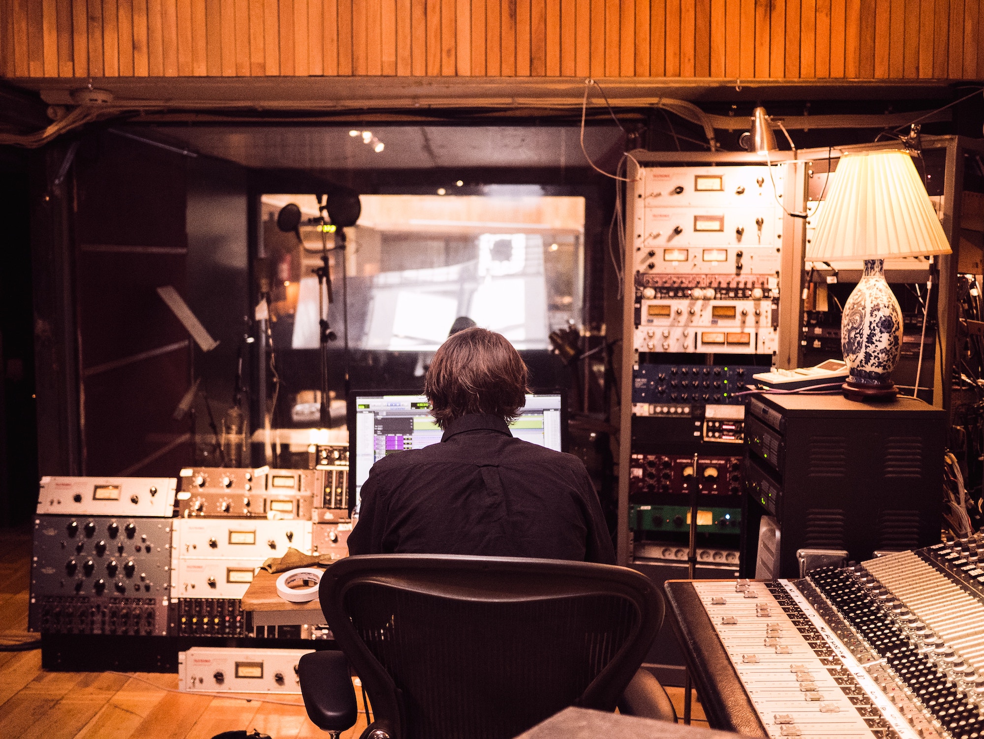 A musician working at a soundboard in a recording studio.