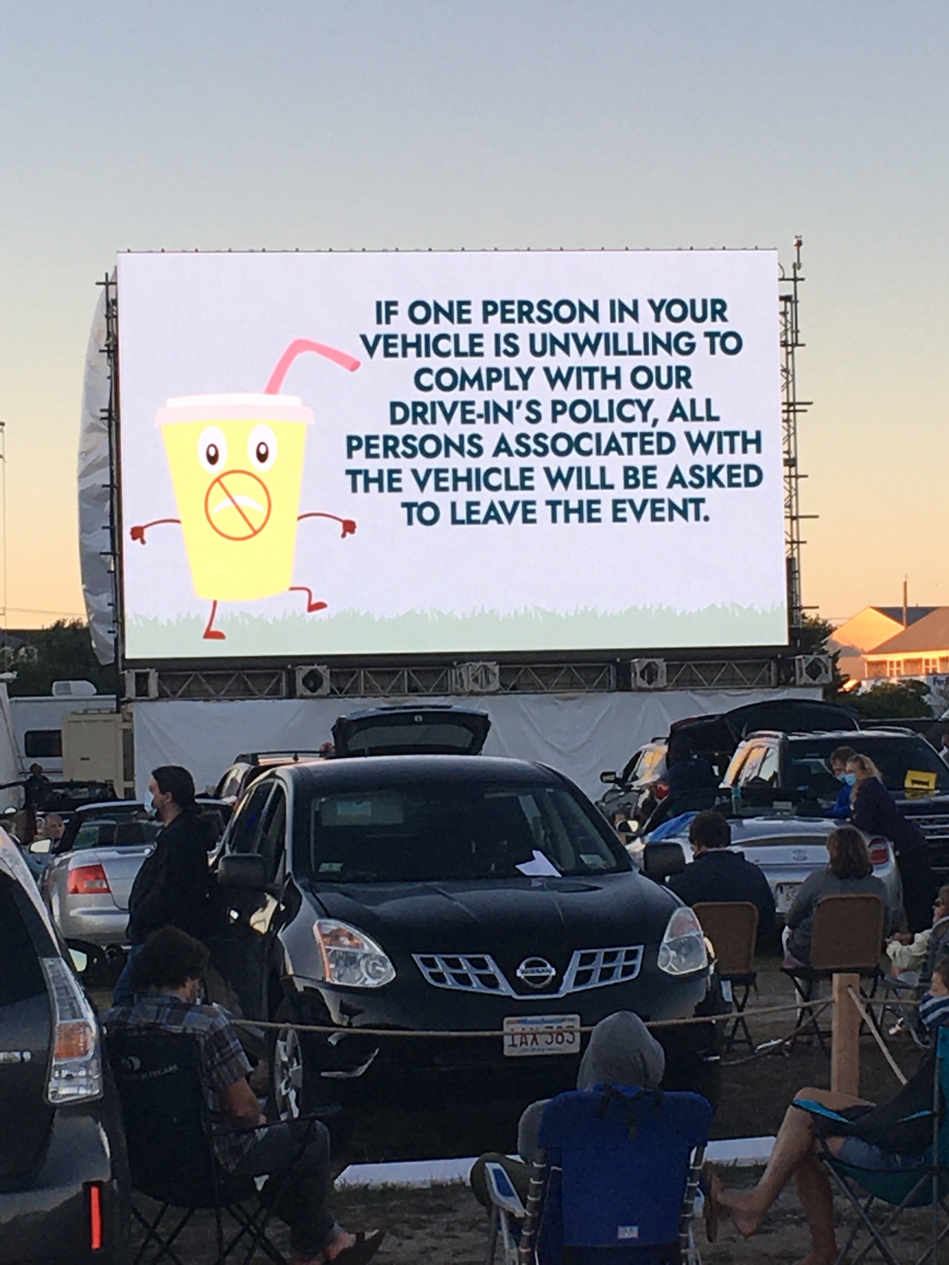 Signage during a drive-in concert at Yarmouth Drive-In shows a cup wearing a face mask and a foreboding message.