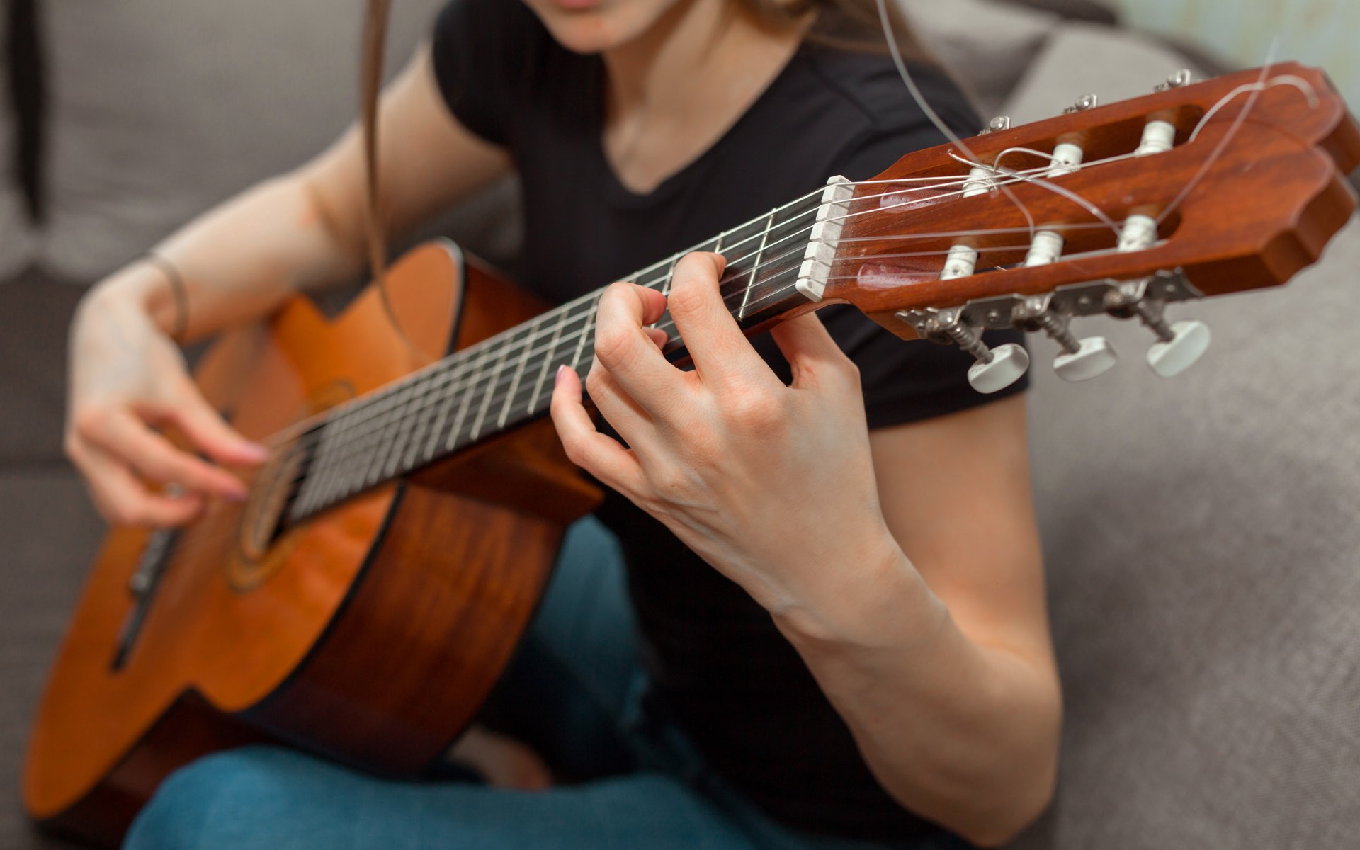 woman playing classical guitar on a couch