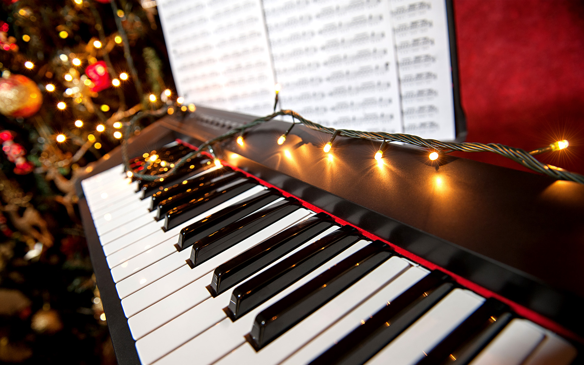 A piano is shown with holiday lights sparkling on the keys and in the background.