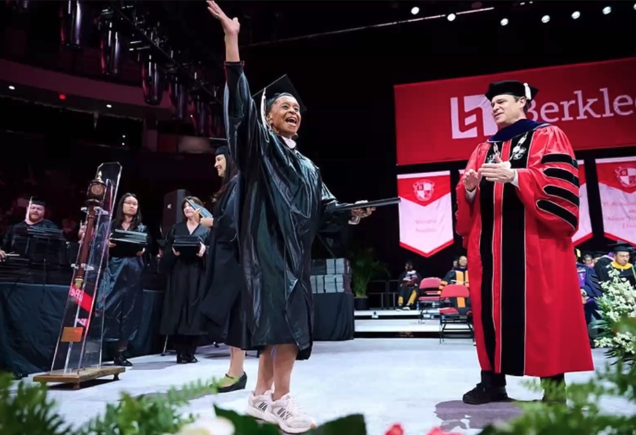 Marchell Jackson, a 75-year-old graduate of Berklee Online gives a wave as she crosses the stage at Commencement.