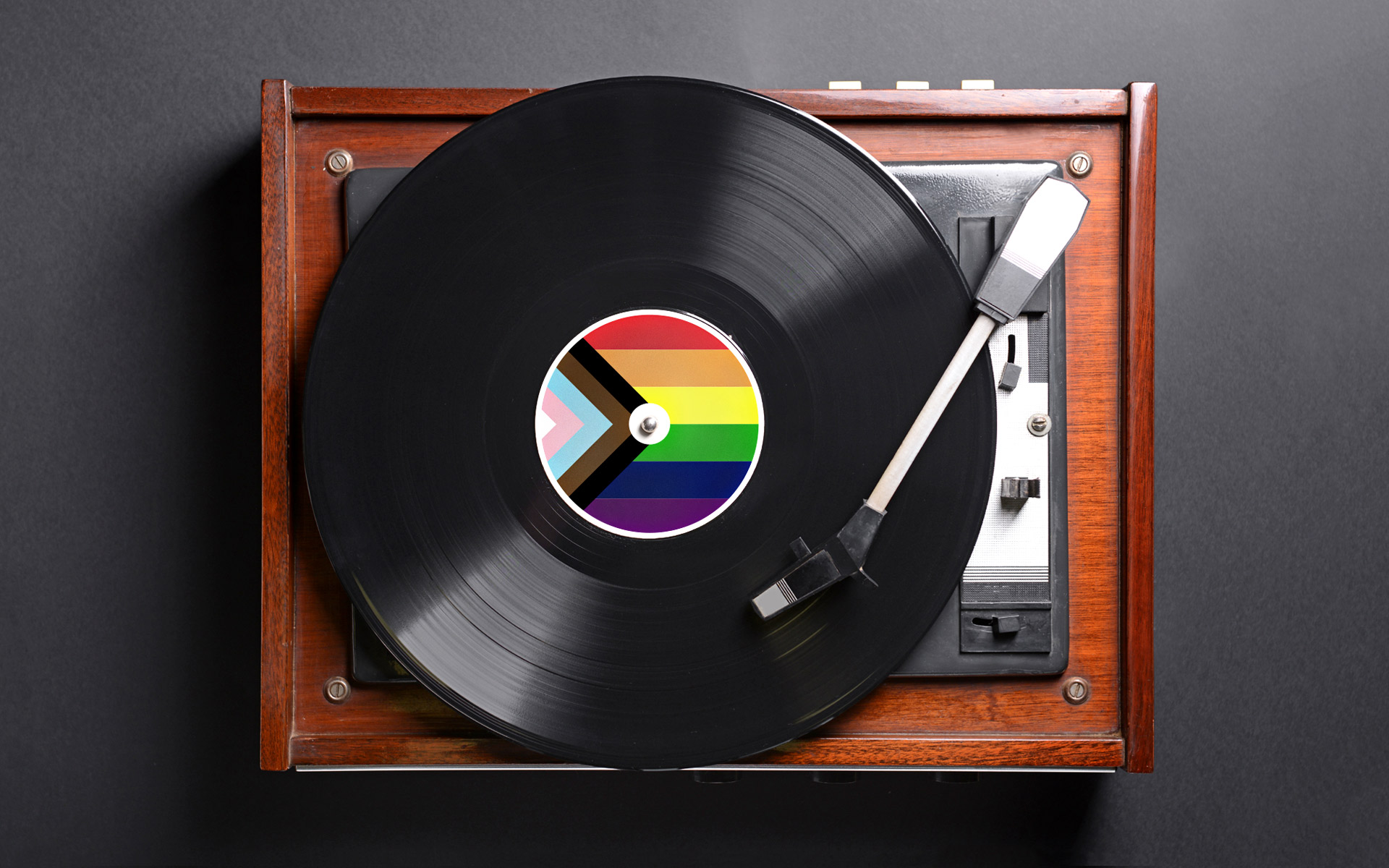 Vinyl record featuring the progress pride flag on a turn table.