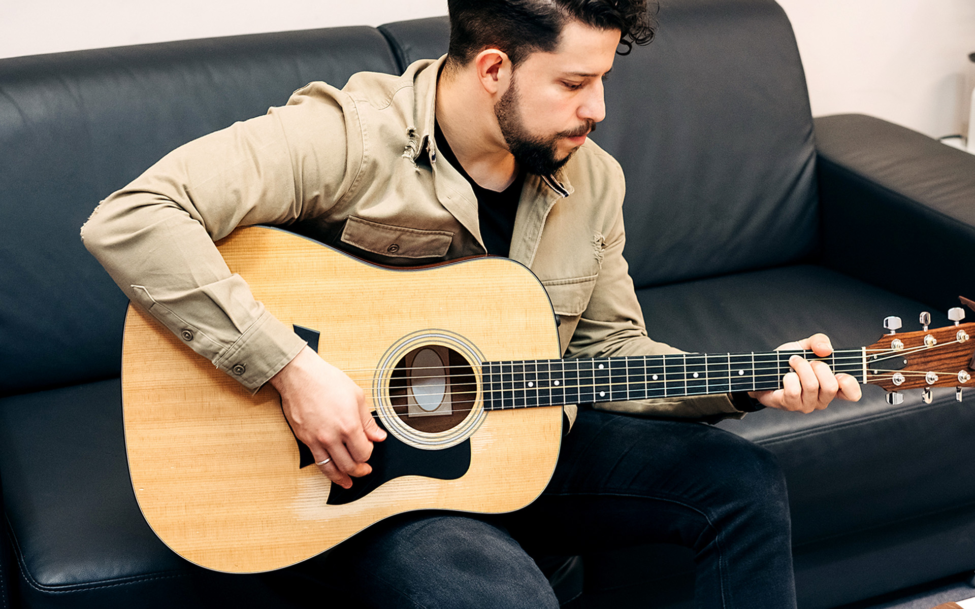 A man plays common chord progression on an acoustic guitar.
