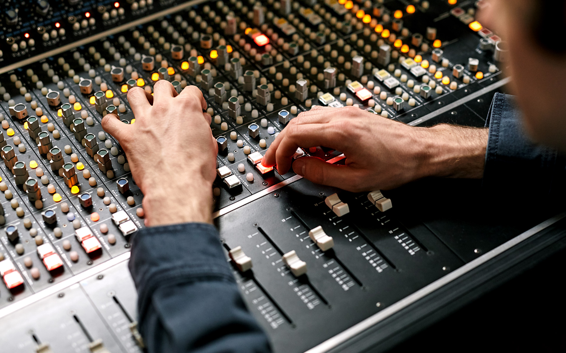 Hands on a sound board in a recording studio.