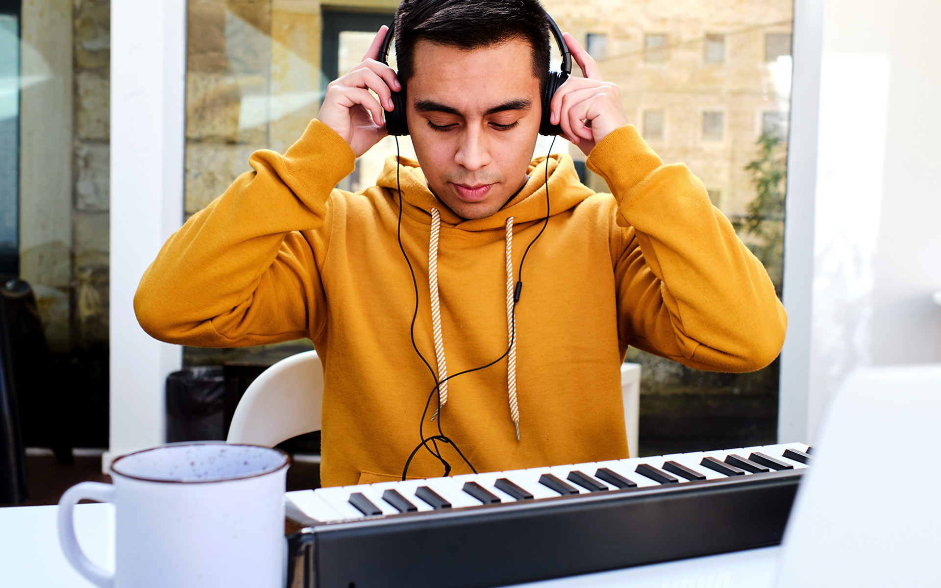 A young music listener puts on his headphones and prepares an intense session of ear training, which we can surmise from his huge cup of coffee.