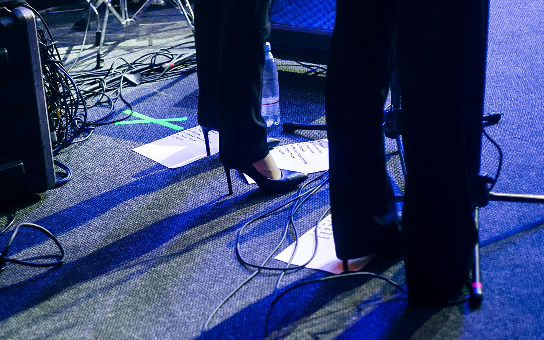 Two musicians standing on stage with a written setlist at their feet