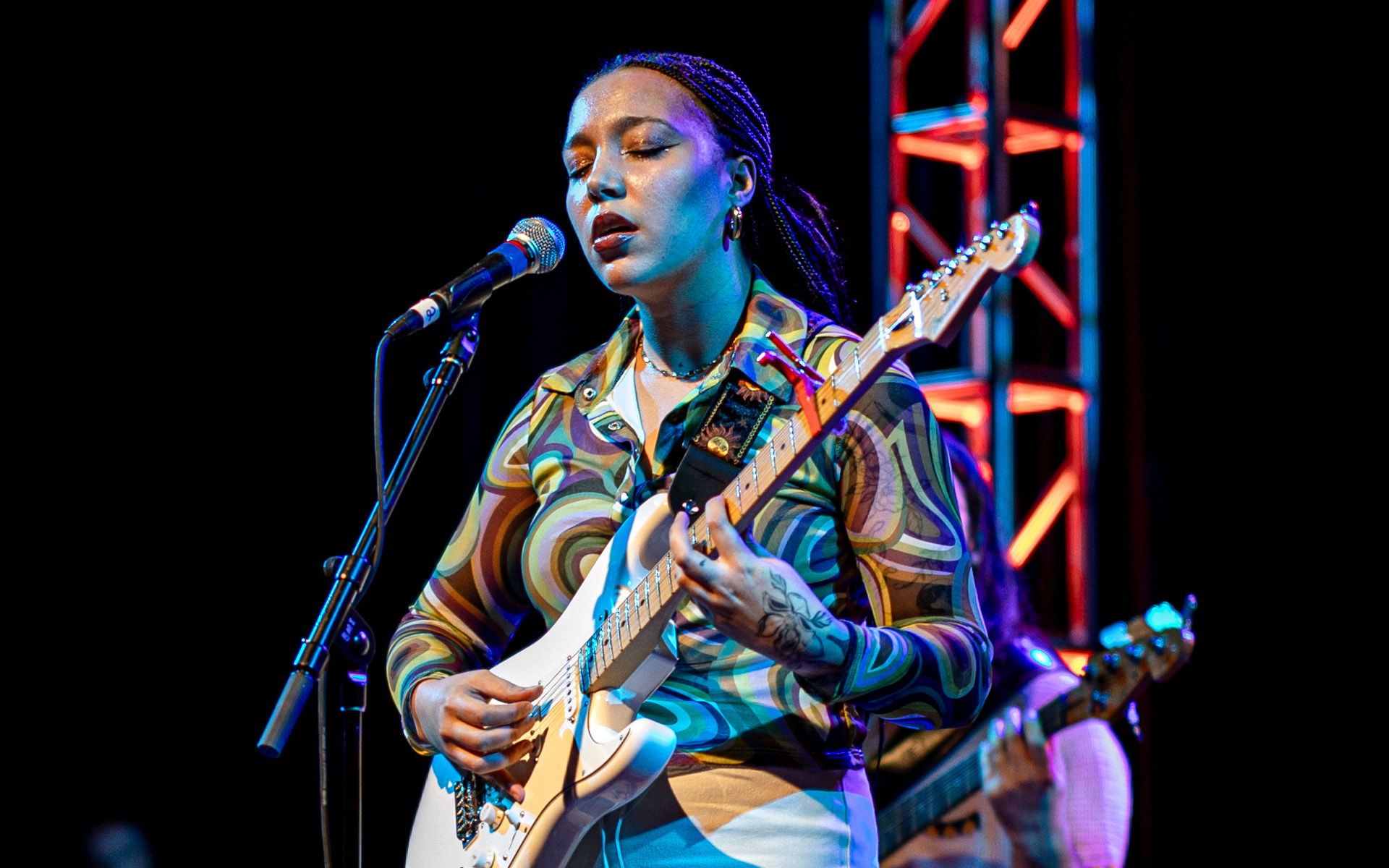 Berklee Online student and musician Julia Pratt is pictured, holding a guitar and performing in concert at the Umbrella Arts Center in Concord, MA, where she opened for Brandi Carlile.