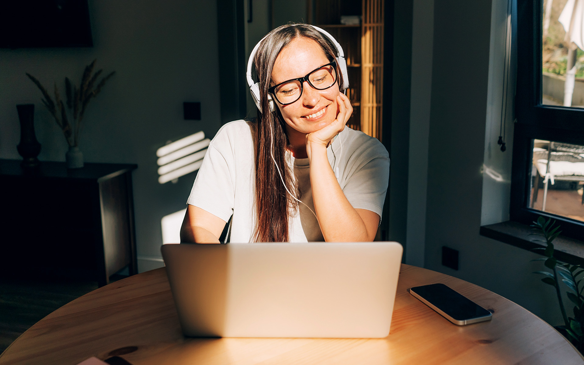 A student sitting at a table in their home on a laptop.