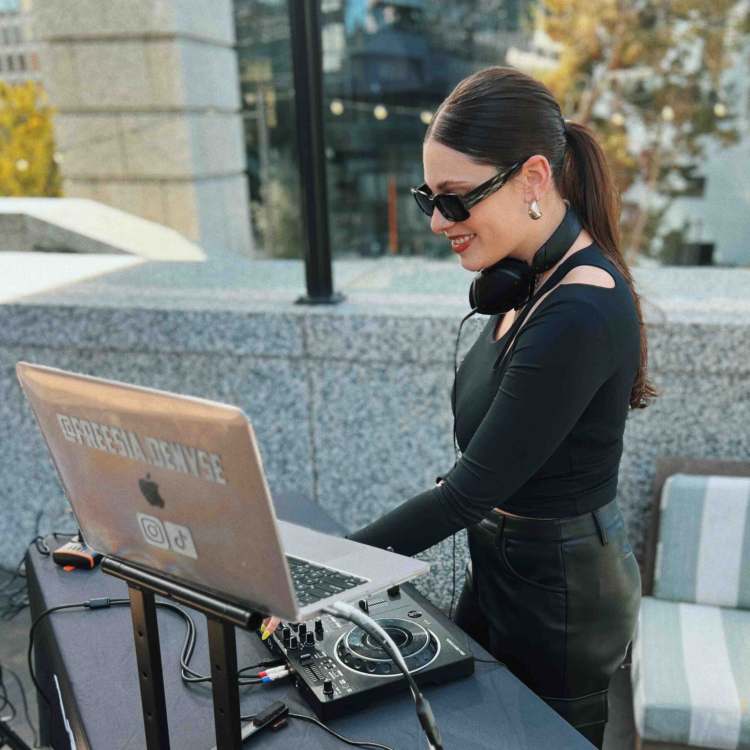 Freesia DJing at a booth with her laptop and controller