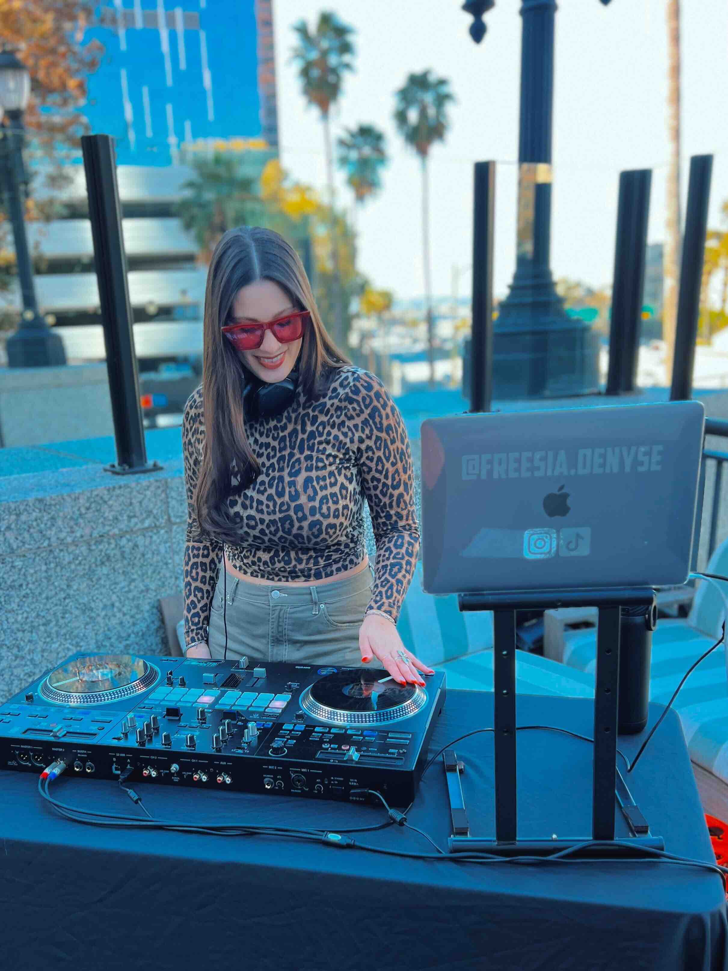 Freesia DJing at a booth with her laptop and controller