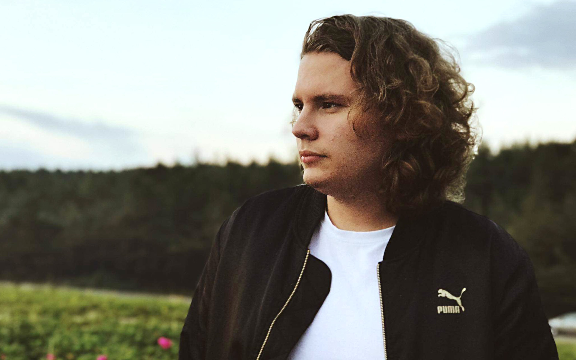 Berklee Online student Vitas Svigaris is pictured in a field, staring out into the distance.