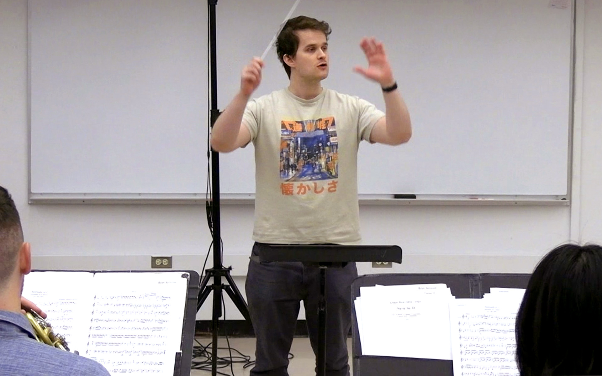 Nathaniel Harder is shown conducting musicians.
