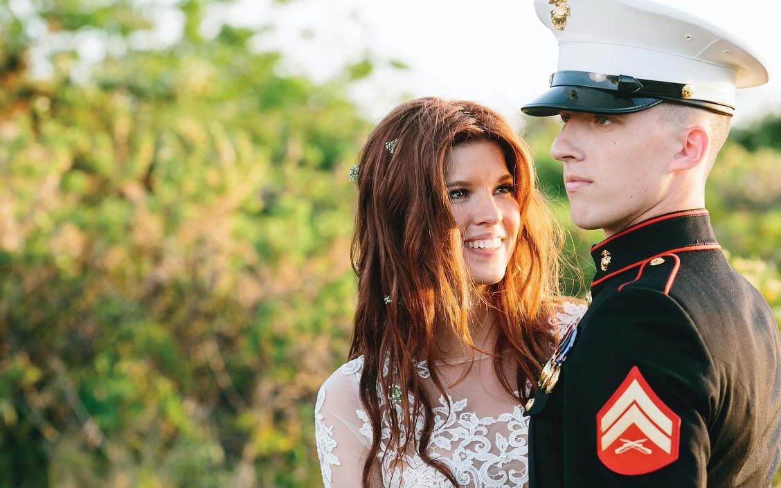 Tim and Kelly Donley are pictured at their wedding. Kelly is wearing a white dress and Tim is wearing a Marine uniform.