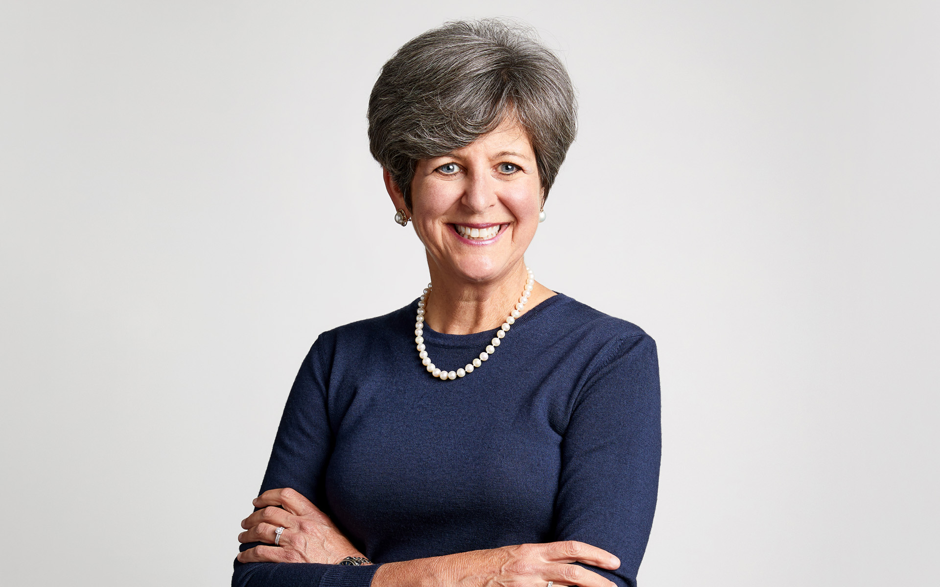 Berklee Online co-founder and CEO Debbie Cavalier is pictured smiling and crossing her arms, standing against a white background.