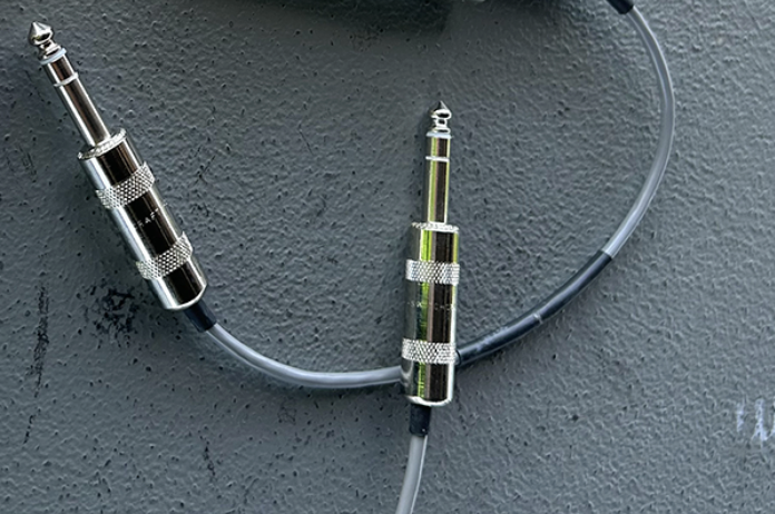 A screen grab of a quarter-inch TRS cable is pictured in a grey background with silver endings