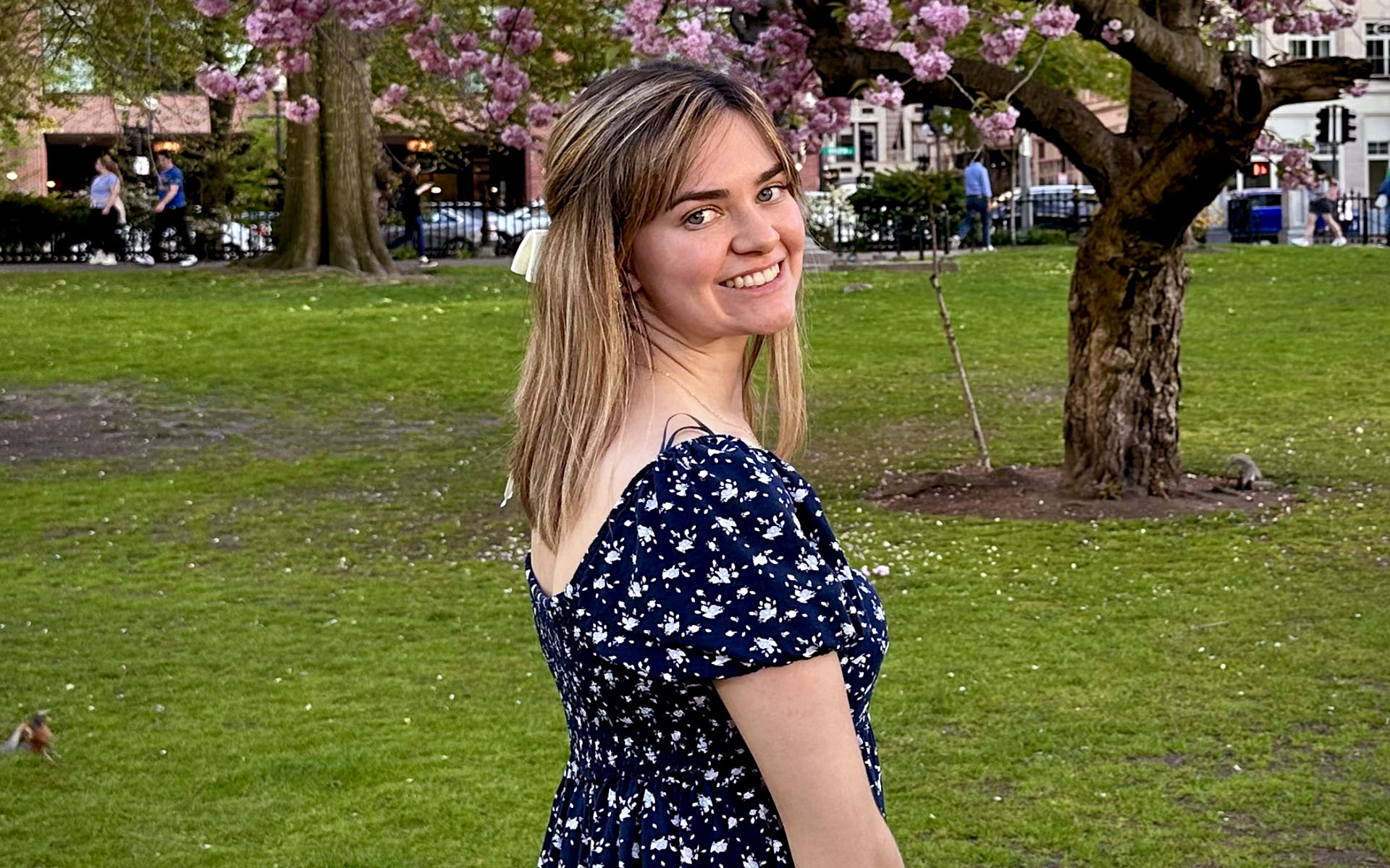 Mattie Diaz standing in front of a blossoming tree looking over her shoulder