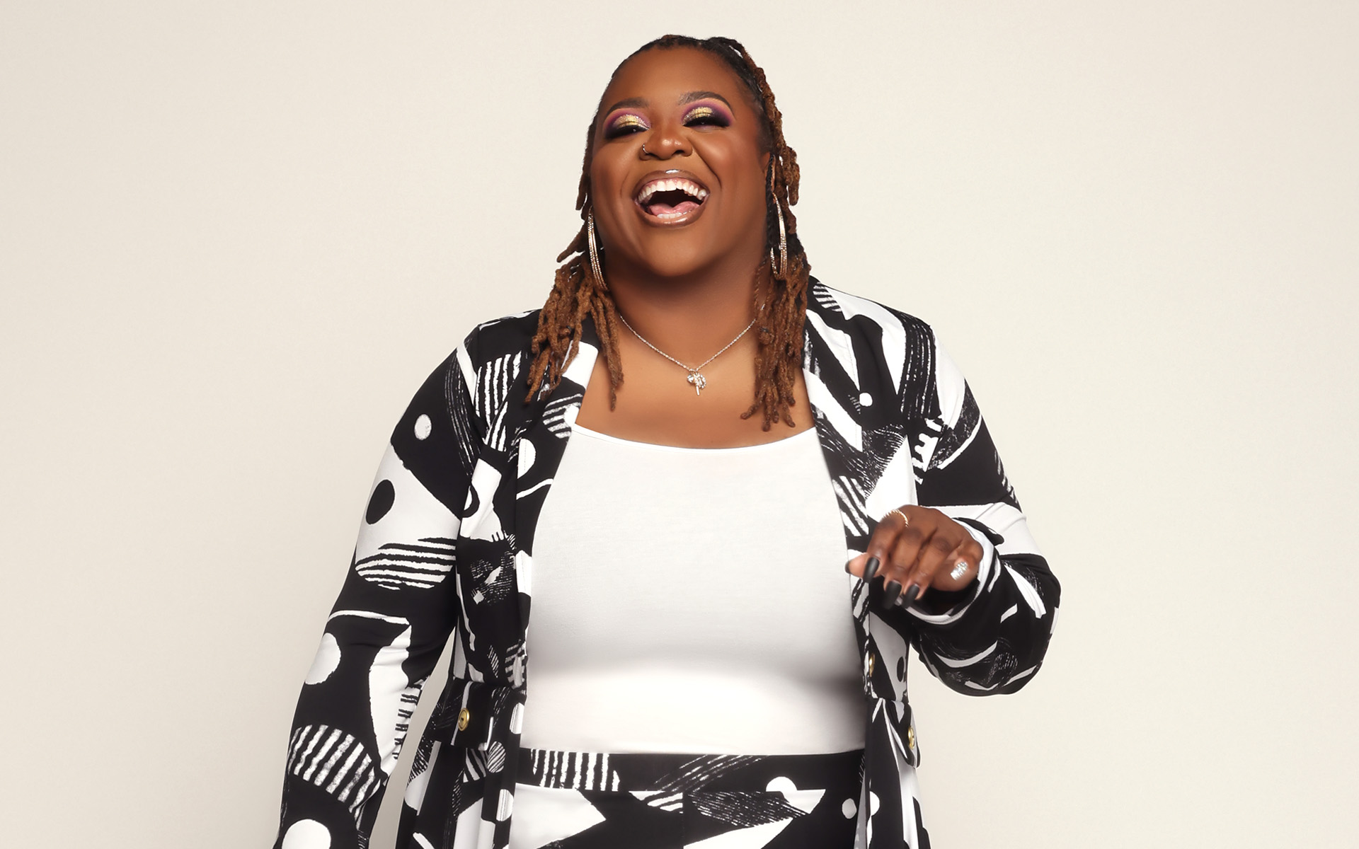 Chadney Christle smiling widely, wearing a black and white geometric suit.