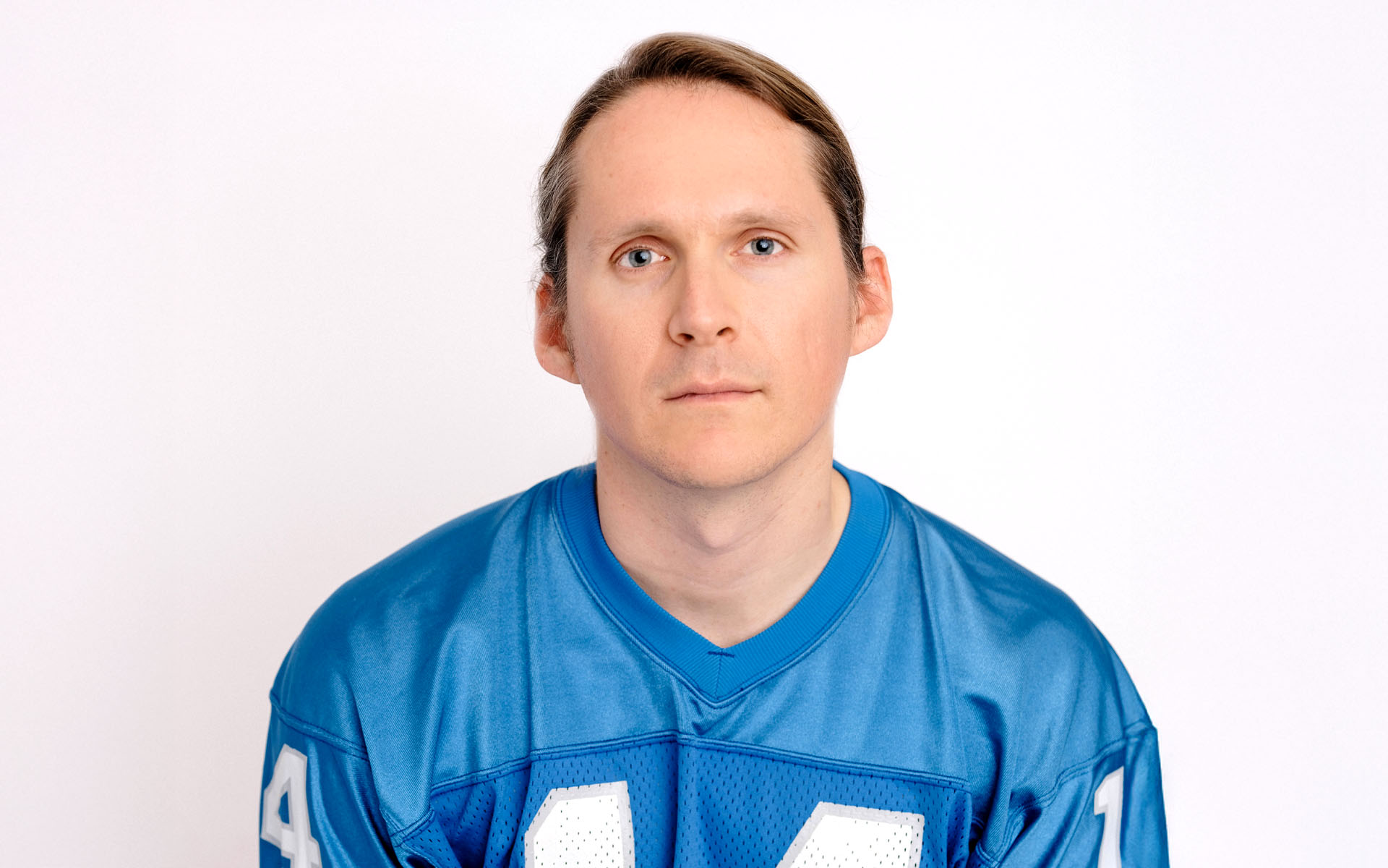 A headshot of Joshua on a white background wearing a blue shirt.