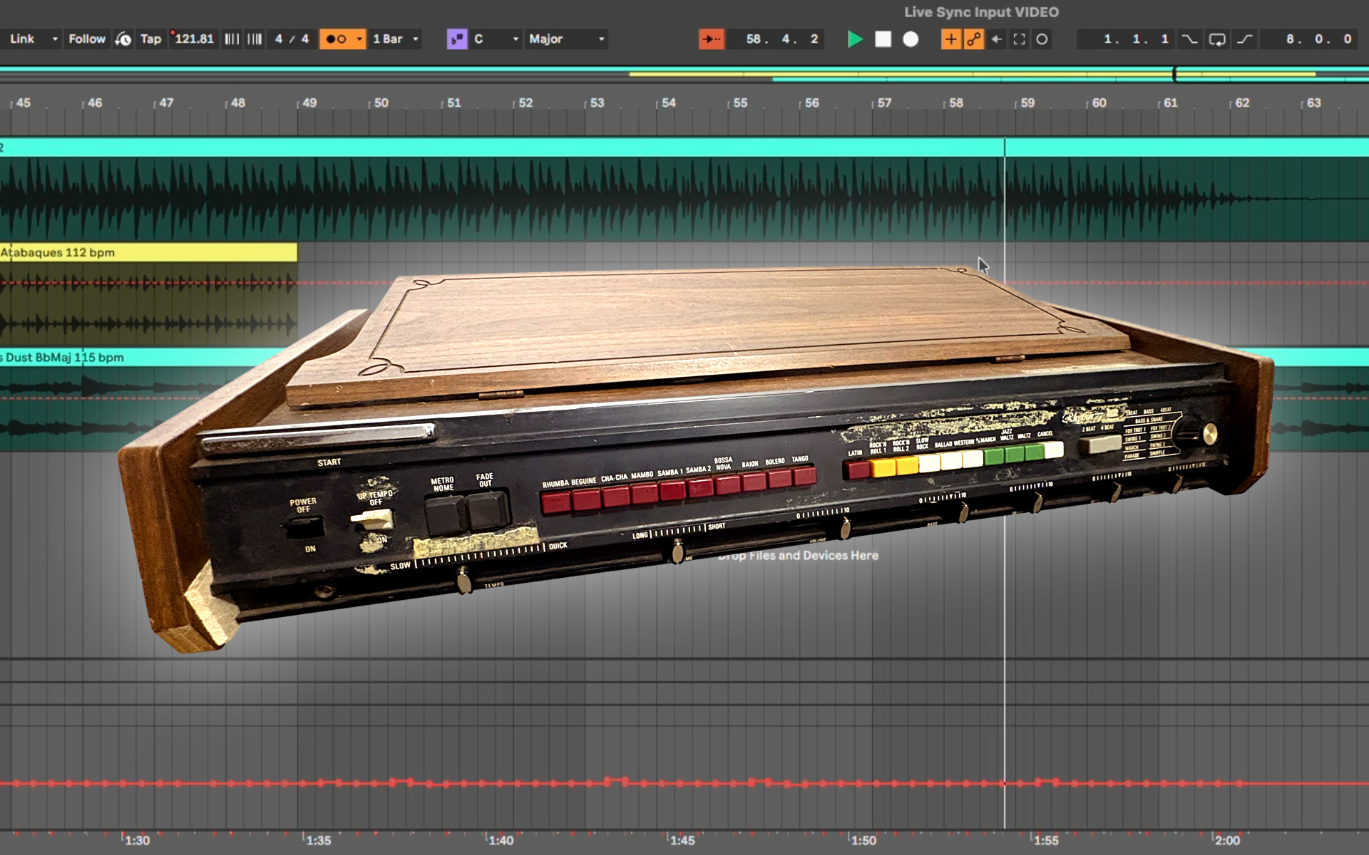 A vintage drum machine is pictured against the backdrop of a modern DAW interface on Ableton.